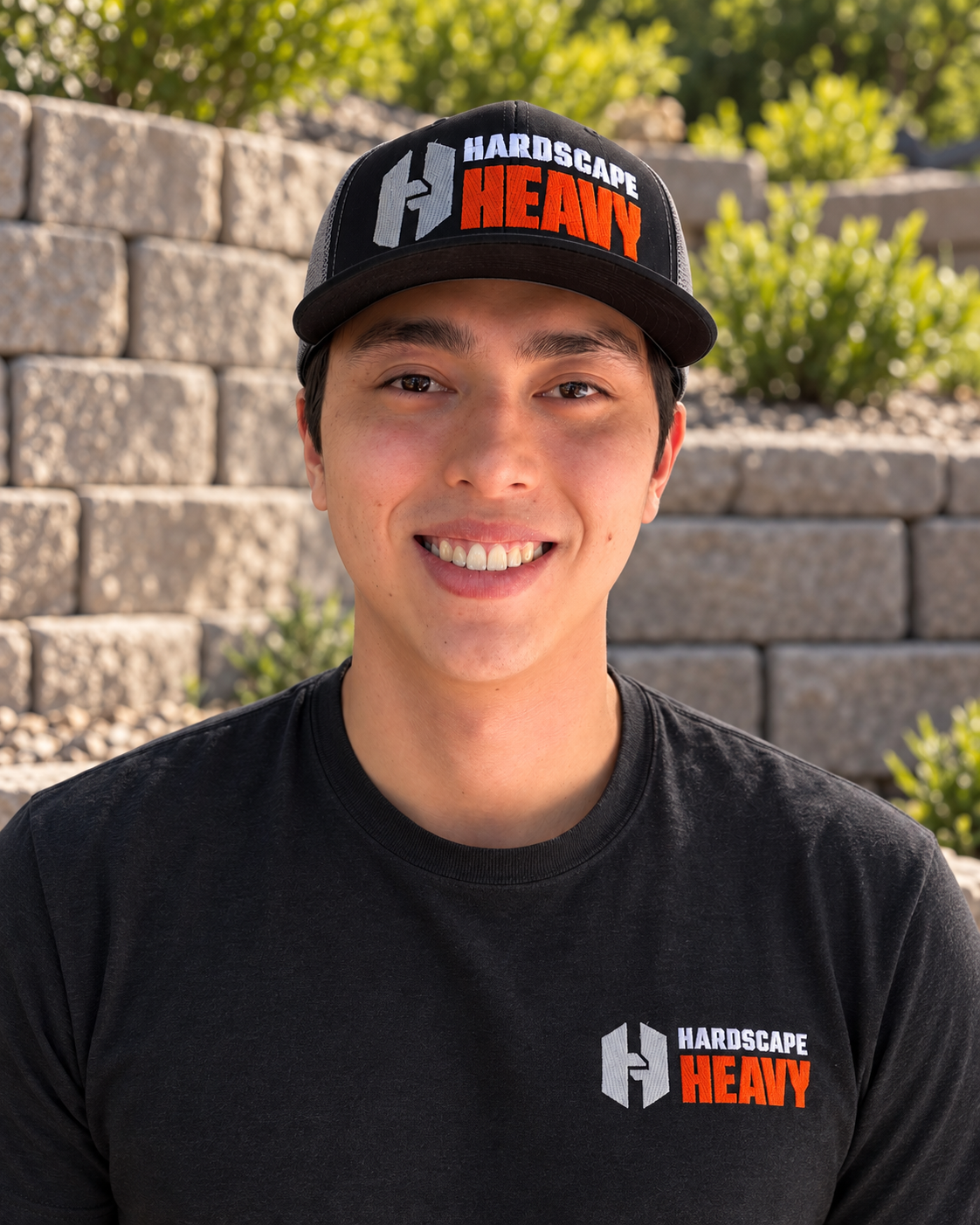 Andrew Brawders, owner and founder of Hardscape Heavy, in front of a block retaining wall