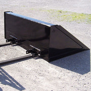 Arrow fork mounted bucket resting on gravel with a set of fork tines slid into its pockets, showing how the bucket seats over existing forks