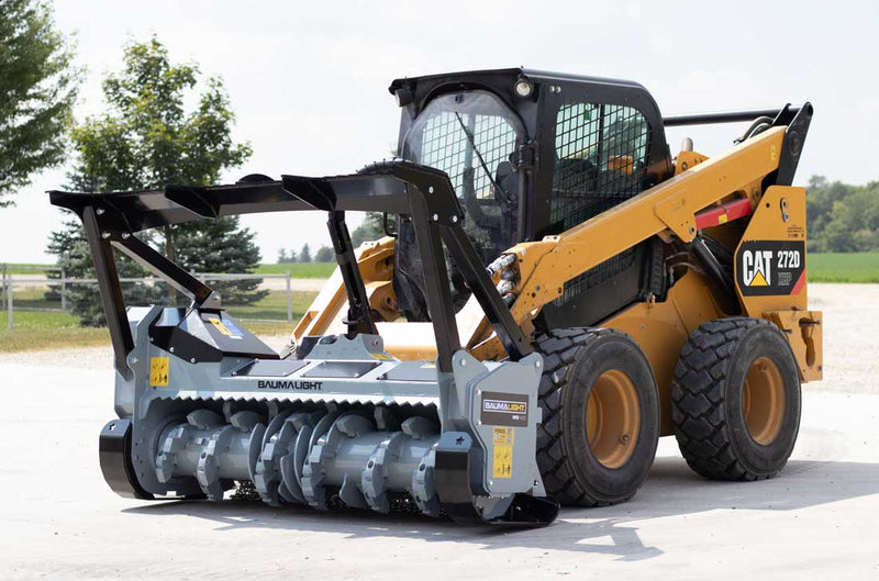 Three-quarter view on pavement of a CAT 272D skid steer with the MS1472 and its black stepped push bar frame raised