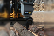 Close view of the RSX380 head and cone above split logs, the operator visible in the cab