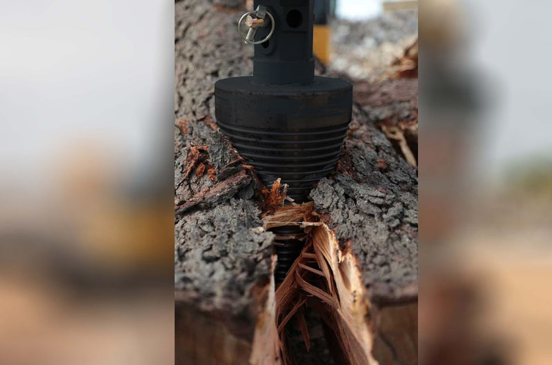 Close view of the splitter cone driven into a log, splitting the timber along the grain