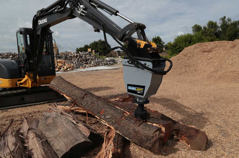 RSX380 on a Deere excavator arm working a log over a bed of wood chips