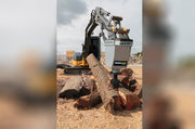 RSX380 splitting a log beside stacked firewood, the head on an excavator arm