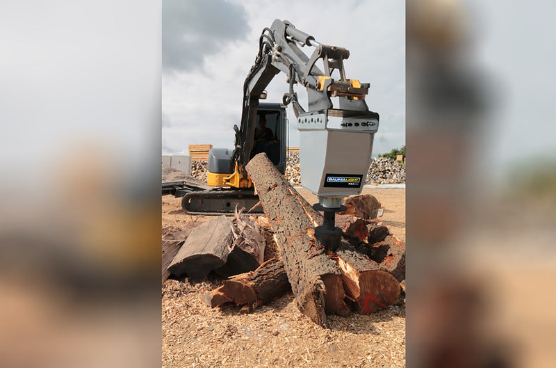 RSX380 splitting a log beside stacked firewood, the head on an excavator arm