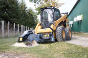 S24 on a CAT 272D skid steer throwing chips beside a green shed