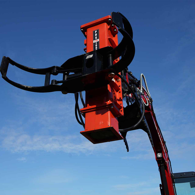 Eterra PDX-1000 excavator post driver with grapple arms open, raised on a red excavator boom against a blue sky