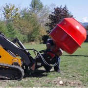 Worker fitting a red cement mixing bowl to the Eterra auger drive on a yellow tracked mini skid steer on a lawn, showing the drive carrying a separate mixing bowl attachment