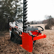 Sickle bar mower mounted on a white Bobcat MT100 mini track loader in a leaf-covered field, with the cutter bar raised vertically and the orange head at ground level