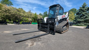 Glacier hydraulic pallet forks mounted on a compact track loader, forks extended forward on a paved lot