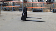 Glacier 8000 pallet forks on pavement with a strap rack behind, side view