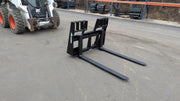 Glacier 8000 pallet forks on pavement with a skid steer behind, angled view