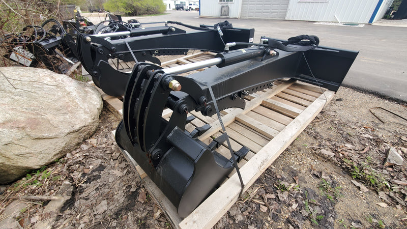 Glacier backhoe attachment strapped to a pallet outdoors, showing the boom, cylinder, thumb, and bucket