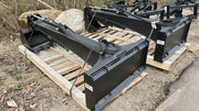 Two Glacier backhoe attachments strapped to pallets in a gravel yard, showing the boom profile and quick-attach plates