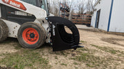 Glacier Extreme rake and brush grapple lowered to bare ground, three-quarter view showing the curved grapple arms