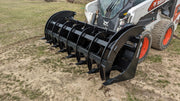 Glacier Extreme rake and brush grapple on a skid steer in a field, angled view along the tine bar
