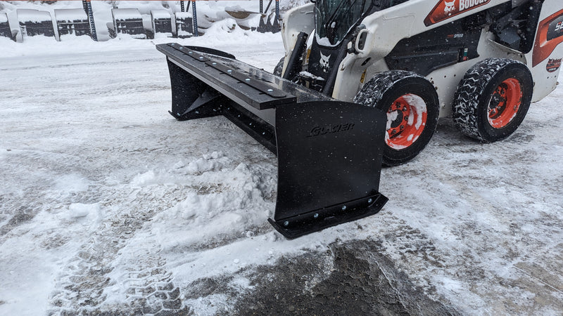 Glacier HD snow pusher pushing snow on a skid steer, three-quarter view on a snowy lot