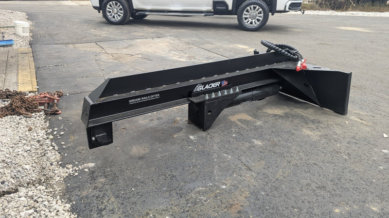 Glacier log splitter on pavement beside a truck, showing the beam, cylinder, hose, and the wedge end