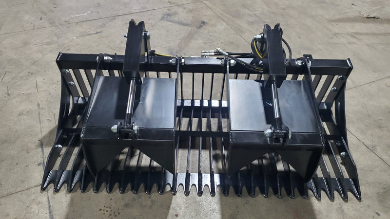 Glacier rock and brush grapple on a shop floor, head-on view across the wide tine bank with bolt-on side plates