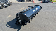 Glacier rotary tiller on pavement, showing the exposed tines along the rotor and the hydraulic connections