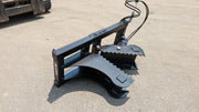 Glacier tree puller on pavement beside a track loader, showing the curved jaws and the branded frame