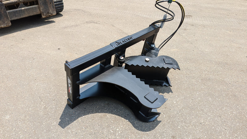 Glacier tree puller on pavement beside a track loader, showing the curved jaws and the branded frame