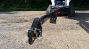 Glacier truss boom extended forward from a compact track loader on gravel, with the hook assembly at the boom tip