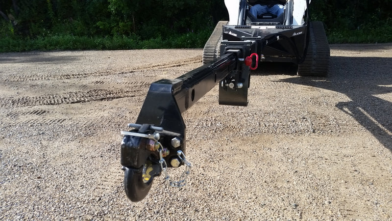 Glacier truss boom extended forward from a compact track loader on gravel, with the hook assembly at the boom tip