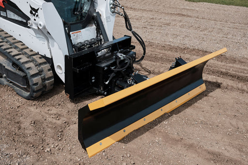 HitchDoc 6-Way Dozer Blade with a yellow top rail and black moldboard, mounted on a white Bobcat compact track loader on gravel, angled view showing the mount frame, hydraulic hoses and the bolted cutting edge