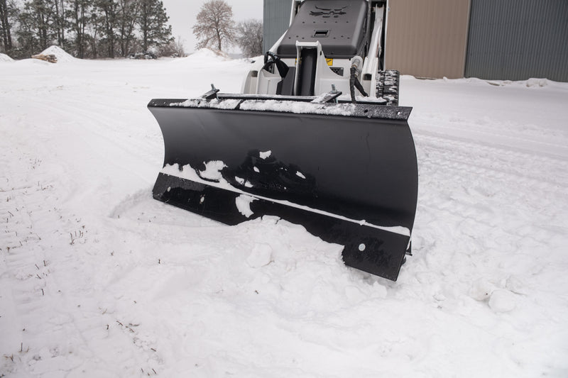 Head-on view of the HitchDoc mini skid steer angle blade set straight, showing the full face of the rolled moldboard, the bolted cutting edge along the bottom and the skid shoe at the blade end