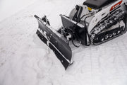 HitchDoc mini skid steer angle blade angled left, seen from above and in front, showing the moldboard, both trip springs, the A-frame push frame and the quick-tach mount plate on a Bobcat mini track loader