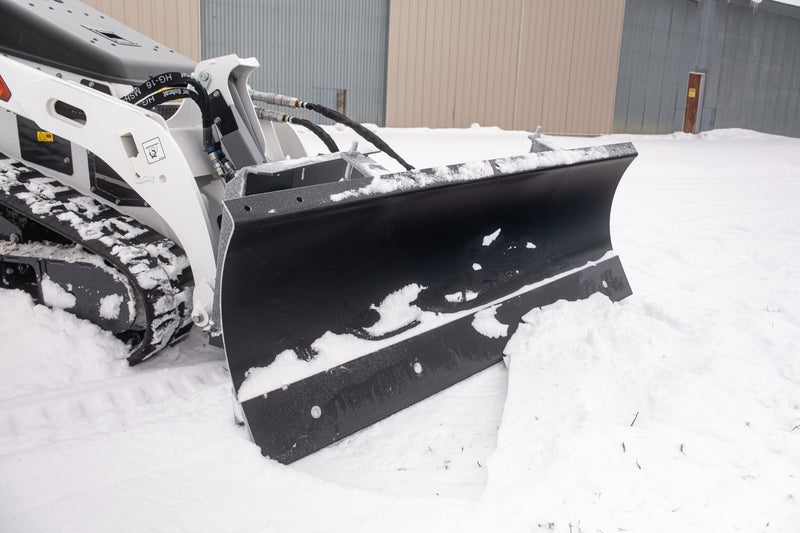 HitchDoc mini skid steer angle blade from the carrier side, showing the quick connect hydraulic couplers and hoses running from the loader arms to the blade, the mount frame and the end plate of the moldboard