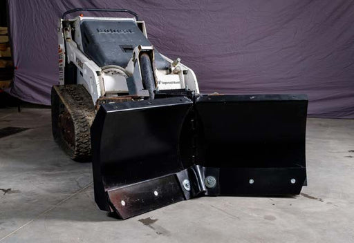 HitchDoc mini skid steer V-blade on a white Ingersoll Rand mini track loader indoors, both wings set forward in the scoop position on the centre hinge, with the bolted reversible cutting edges along the bottom of each wing