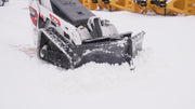 HitchDoc mini skid steer V-blade working on a Bobcat MT100 mini track loader, wings set offset on the centre hinge to cast snow to one side, with the bolted cutting edge riding down to bare ground
