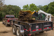 HitchDoc Push-Off Bucket near the end of its eject stroke, the load broken up and dropping into the dump trailer with the bucket still held level