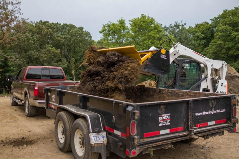 HitchDoc Push-Off Bucket near the end of its eject stroke, the load broken up and dropping into the dump trailer with the bucket still held level