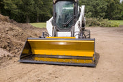 HitchDoc Push-Off Bucket seen head-on from the front on a white Bobcat skid steer, the yellow extractor blade across the back of the empty bucket and the bolted cutting edge resting on packed dirt