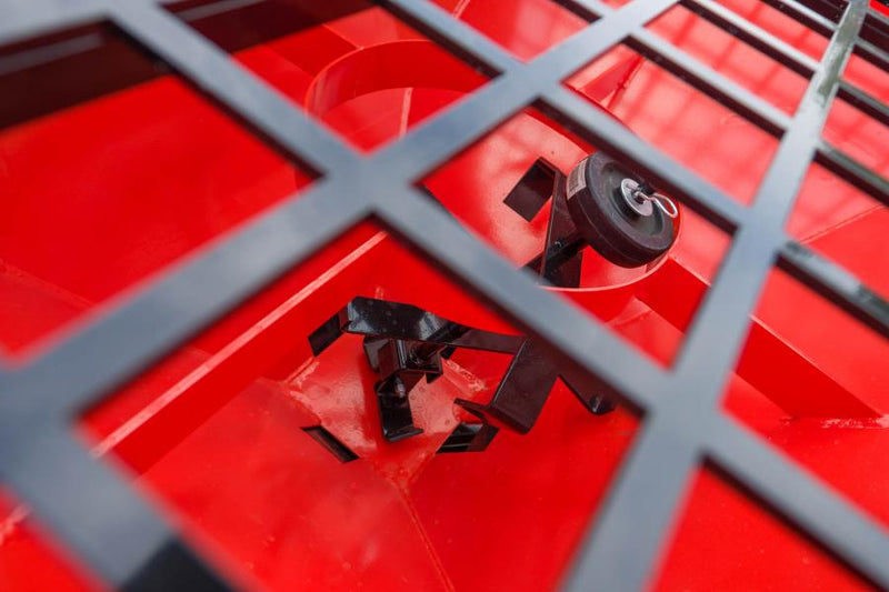 Looking down through the HitchDoc Sandpiper protective grate into the red hopper, showing the black steel agitator and the spinner shaft at the base of the cone
