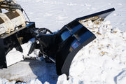 HitchDoc V-Blade turned to one side of the machine, showing the universal quick-tach mount plate, a trip spring, the double hydraulic cylinders and both wings with their cutting edges