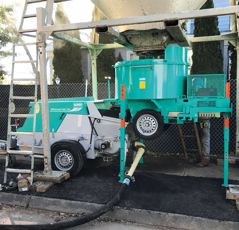 IMER Booster 20 towable diesel concrete piston pump, positioned under a Mix 750 mixer on site