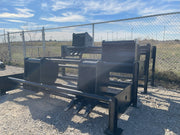 Bucket racks in a rental yard with a toothed bucket stored on the near rack