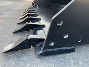 Close-up along the tooth bank of the extreme duty bucket, showing the tooth shanks and the side plate mounting holes