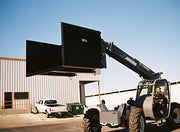 Telehandler lifting the loaded trash hopper to height