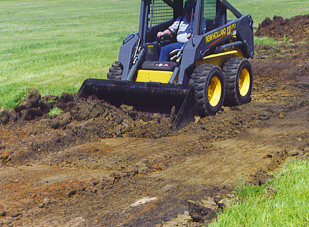 Skid steer back-dragging soil level with the heavy duty bucket's square bottom