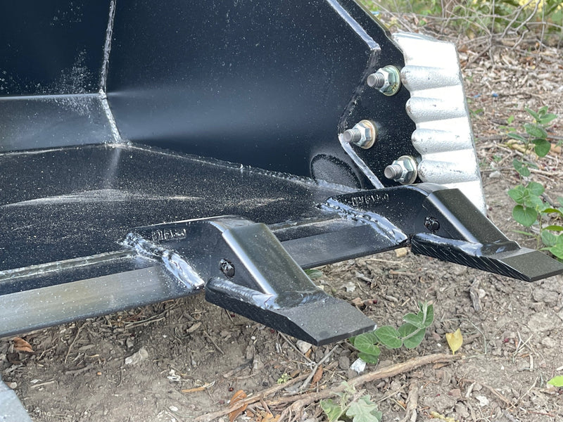 Close-up of a bolt-on side cutter showing the through-bolts and nuts inside the bucket wall