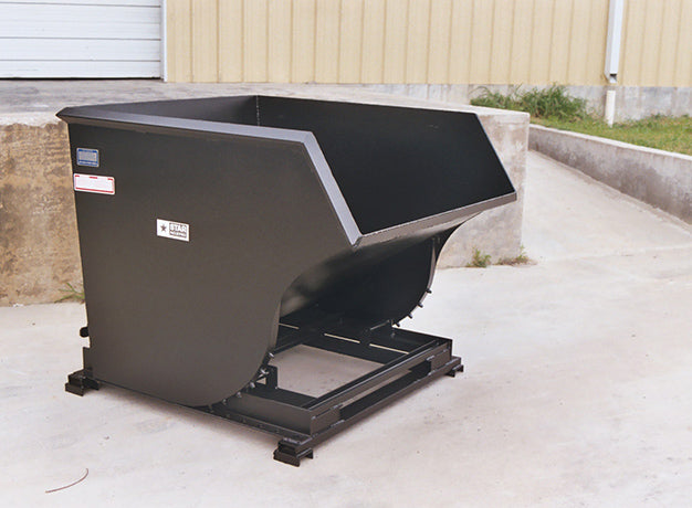 Self-dumping hopper standing on a concrete apron outside a building