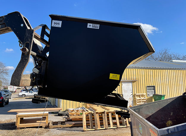 Self-dumping hopper on the boom above stacked pallets and a skip