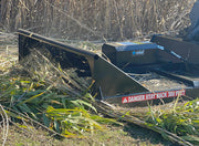 Brush cutter deck seen from the side over freshly cut cane on the ground