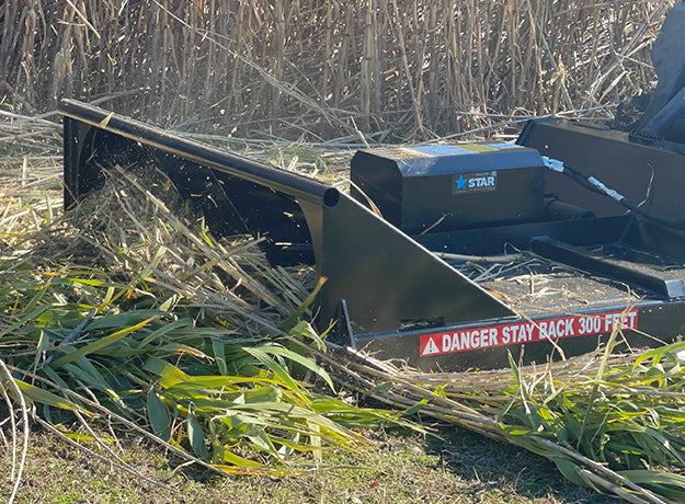 Brush cutter deck seen from the side over freshly cut cane on the ground