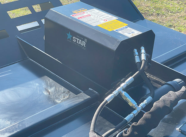 Close-up of the brush cutter motor housing with the Star decal and the hydraulic hoses running into it