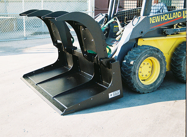 Grapple bucket mounted on a skid steer outdoors, arms raised, Star decal visible on the bucket front